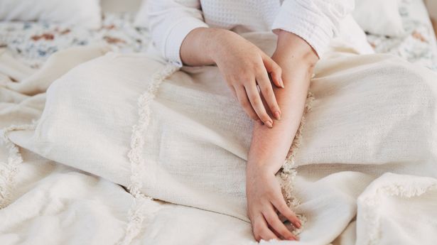 A woman touching the skin on her arm, generic