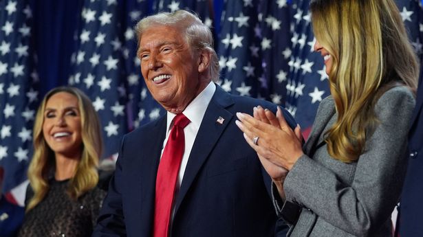 President Donald Trump stands on stage with former first lady Melania Trump and Lara Trump