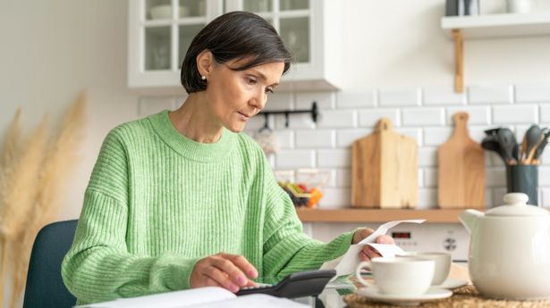 A woman looking at her finances with receipts, bills and a calculator